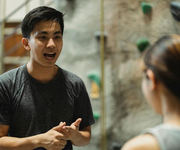 Instructor kindly explaining an exercise to a new member in the gym.